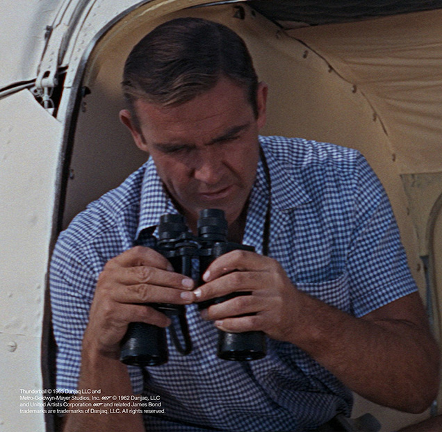 photo © Danjaq LLC, MGM, United Artists Sean Connery as James Bond in Thunderball wearing a blue Gingham shirt during the first helicopter flight with Felix Leiter